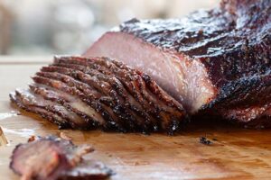 Cooked and sliced brisket on a wood cutting board