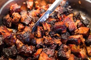 Burnt Ends barbecue meat with tongs