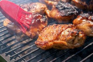 Chicken thighs on barbecue being basted