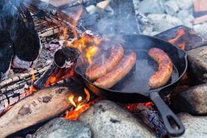 Campfire cooking sausages in skillet