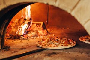 Pizza being placed in a wood fire pizza oven